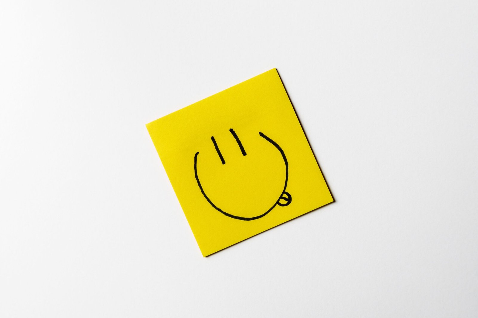 A simple, hand-drawn smiley face on a yellow sticky note against a white background.